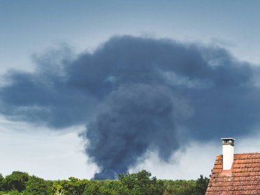 Yanan bir plastik geri dönüşüm yeri, gökyüzü mavi yaz gününde koyu siyah bir duman yığınına neden olur. Tehlike, keder. Terörist saldırı ya da patlama. Çevre felaketi