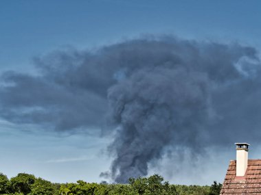 Yanan bir plastik geri dönüşüm yeri, gökyüzü mavi yaz gününde koyu siyah bir duman yığınına neden olur. Tehlike, keder. Terörist saldırı ya da patlama. Çevre felaketi