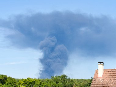 Yanan bir plastik geri dönüşüm yeri, gökyüzü mavi yaz gününde koyu siyah bir duman yığınına neden olur. Tehlike, keder. Terörist saldırı ya da patlama. Çevre felaketi