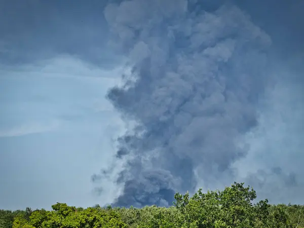 Yanan bir plastik geri dönüşüm yeri, gökyüzü mavi yaz gününde koyu siyah bir duman yığınına neden olur. Tehlike, keder. Terörist saldırı ya da patlama. Çevre felaketi