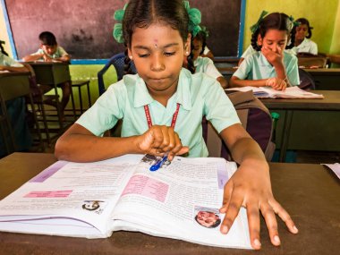 PUDUCHERRY, İNDİA - Aralık 2018. Tanımlanamayan, devlet okulu üniformalı, sandalyeye oturmuş kapalı alanda kitap okuyan ciddi sınıf arkadaşları. Okul gençlerinin portresi.