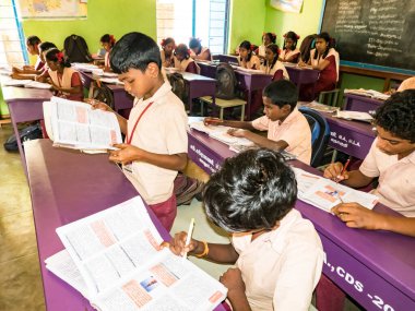 PUDUCHERRY, İNDİA - Aralık 2018. Devlet okulunda üniformalı tanımlanamayan mutlu sınıf arkadaşları evde oturup kitap okuyor. Fakir gençlerin okul portresi arkadaşlığın keyfini çıkarıyor..