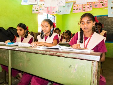 PUDUCHERRY, İNDİA - Aralık 2018. Devlet okulunda üniformalı tanımlanamayan mutlu sınıf arkadaşları evde oturup kitap okuyor. Fakir gençlerin okul portresi arkadaşlığın keyfini çıkarıyor..