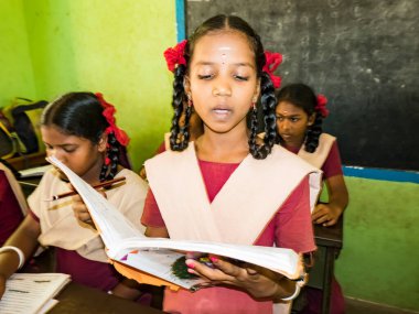 PUDUCHERRY, İNDİA - Aralık 2018. Tanımlanamayan, devlet okulu üniformalı, sandalyeye oturmuş kapalı alanda kitap okuyan ciddi sınıf arkadaşları. Okul gençlerinin portresi.