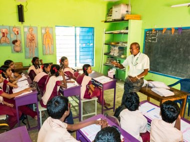 PUDUCHERRY, İNDİA - Aralık 2018. Devlet okulunda üniformalı tanımlanamayan mutlu sınıf arkadaşları evde oturup kitap okuyor. Fakir gençlerin okul portresi arkadaşlığın keyfini çıkarıyor..