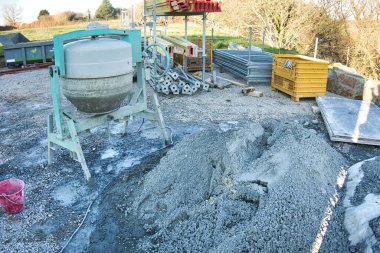 Çimento makinesi kırmızı kovayla çakıl taşlarına yakın. İnşaat çalışıyor