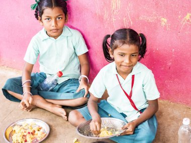 Puducherry, Tamil Nadu, Hindistan - Aralık yaklaşık, 2018. Bazı masala ile pirinç onların sağ eli ile yemek tanımlanamayan zavallı sınıf kızlarla yerde açık havada üzerinde oturan üniformalar. Öğle yemeği zamanı, genel hükümet okulda sağlıksız gıda