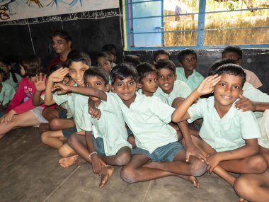 PUDUCHERRY, İNDİA - Aralık 2019. Tanımlanamayan mutlu öğrenciler devlet okulu üniformalı sınıf arkadaşları evde oturup ders çalışıyorlar. Yardım için gülümseyen zavallı çocukların portresi.