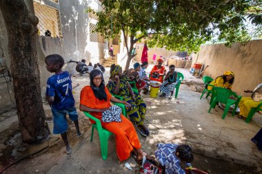 Bour, Senegal - Aralık 2021 civarı. Geleneksel renkte giyinmiş, tanımlanamayan kadınlar açık mutfakta temel gıdalarla yemek pişiriyorlar ama harika yemekler yapıyorlar. Afrika 'da yoksulluk