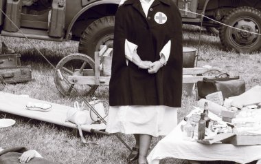 SAINTE MERE L'EGLISE, NORMANDY, FRANCE - JUNE 6 2023. Second world war commemoration. Military camp reconstitution Unidentified nurse with medical equipments next to military tent clipart