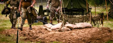 Aziz Michael L 'Eglise, Normandiya, Fransa - 6 Haziran 2023. İkinci Dünya Savaşı anısına. Askeri kamptaki tanımlanamayan askerler siperin yanında makineli tüfek ve kum torbası koruması ile yeniden yapılandırılıyor..