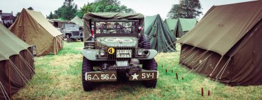 SAINTE MERE L'EGLISE, NORMANDY, FRANCE - JUNE 6 2023. Second world war commemoration. Military camp reconstitution Tents, military american war trucks. clipart