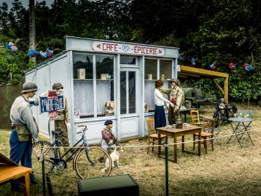 Aziz Michael L 'Eglise, Normandiya, Fransa - 6 Haziran 2023. İkinci Dünya Savaşı anısına. Askeri kamp yeniden yapılandırıldı. Tanımlanamayan eski tip sahte aile, mağazanın yanında, klasik giyimli.