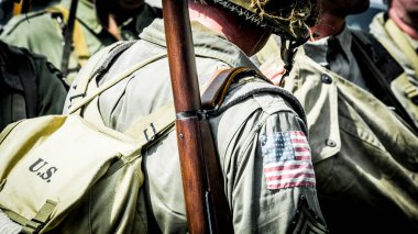 Aziz Michael L 'Eglise, Normandiya, Fransa - 6 Haziran 2023. İkinci Dünya Savaşı anısına. Askeri kamp yeniden yapılandırıldı. Kimliği belirlenemeyen silahlı asker savaş için ağır donanımı kapatıyor.