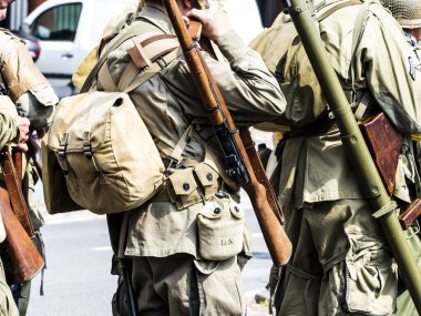 Aziz Michael L 'Eglise, Normandiya, Fransa - 6 Haziran 2023. İkinci Dünya Savaşı anısına. Askeri kamp yeniden yapılandırıldı. Kimliği belirlenemeyen silahlı asker savaş için ağır donanımı kapatıyor.