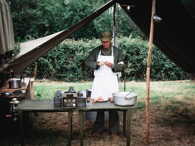 SAINTE MERE L'EGLISE, NORMANDY, FRANCE - JUNE 6 2023. Second world war commemoration. Military camp reconstitution Authentic scene of unidentified army cooker with table tools onions. clipart