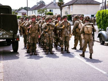 SAINTE MERE L'EGLISE, NORMANDY, FRANCE - JUNE 6 2023. Second world war commemoration. Military camp reconstitution Unidentified soldiers next to bags and military equipments. clipart