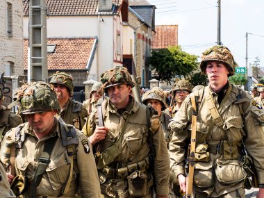 Aziz Michael L 'Eglise, Normandiya, Fransa - 6 Haziran 2023. İkinci Dünya Savaşı anısına. Askeri kamp yeniden yapılandırıldı. Tanımlanamayan silahlı askerler özgürlükten sonra yürüyorlar