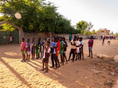Bour, Senegal - CIRCA Mart 2021. Kimliği belirlenemeyen yoksul Afrikalı çocuklar ve dışarıda oynayan gençler.