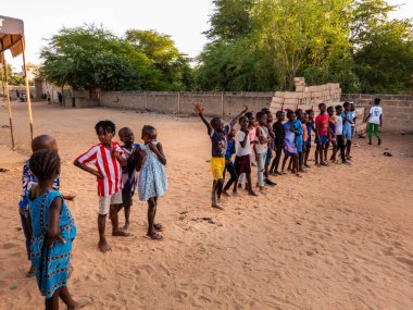 Bour, Senegal - CIRCA Mart 2021. Kimliği belirlenemeyen yoksul Afrikalı çocuklar ve dışarıda oynayan gençler.