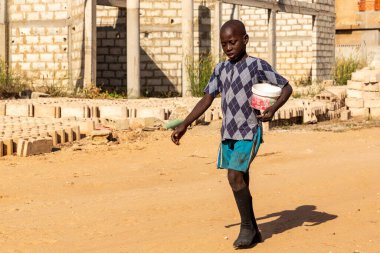 Bour, Senegal - CIRCA Mart 2021. Kimliği belirlenemeyen genç sokak, yiyecek bağışı arıyor. Talibe Kur 'an okulunda