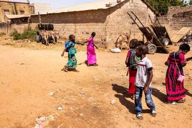 Bour, Senegal - CIRCA Mart 2021. Tanımlanamayan ciddi bir şekilde korkmuş fakir Afrikalı çocuklar ve köydeki gençler kameraya bakıyorlardı..