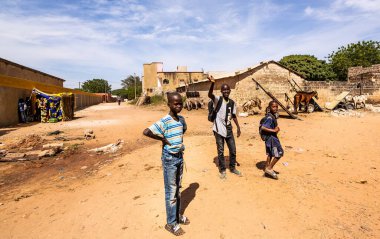 Bour, Senegal - CIRCA Mart 2021. Tanımlanamayan ciddi bir şekilde korkmuş fakir Afrikalı çocuklar ve köydeki gençler kameraya bakıyorlardı..