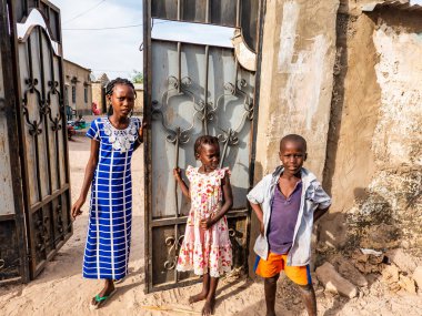 Bour, Senegal - CIRCA Mart 2021. Tanımlanamayan ciddi bir şekilde korkmuş fakir Afrikalı çocuklar ve köydeki gençler kameraya bakıyorlardı..