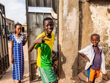 Bour, Senegal - CIRCA Mart 2021. Kimliği belirsiz mutlu, gülümseyen Afrikalı çocuklar ve kameraya bakan gençler..