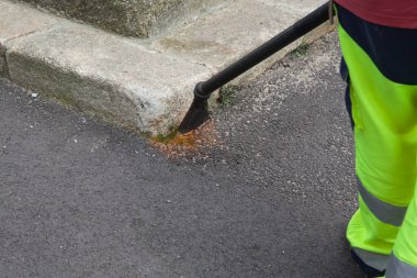 Şehrin sokaklarında yabani otları yakan bir adam. Çevre saygısı. Sarı kumaşlı.
