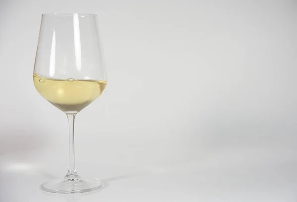 Beyaz arka planda bir bardak beyaz şarap. 