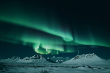 aurora borealis shining in the sky over a snowy landscape in iceland. High quality photo clipart