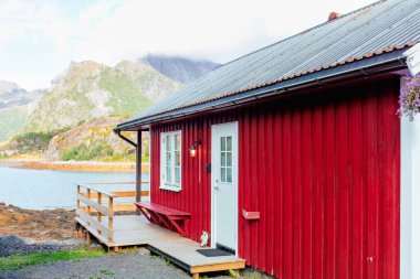 Geleneksel kırmızı kulübe manzaralı ve dağ manzaralı turistler için. Rahatlatıcı bir kaçış için hoş ve güzel bir ortam. Lofoten Adaları, Norveç