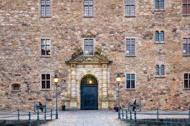 Ortaçağ duvarlarının zengin dokuları ve klasik fenerler ile Orebro Kalesi 'ne açılan gece aydınlatılmış kapı, zamansız tarih duygusunu çağrıştırıyor. Orebro, İsveç.