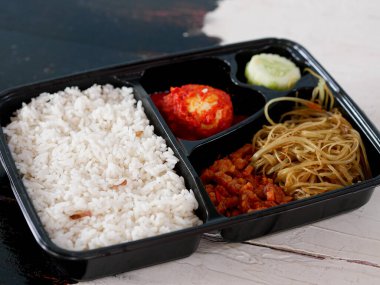 pirinç bento kutusu yanında balado yumurtaları, erişte, tempeh ve salatalık sebzeleri..