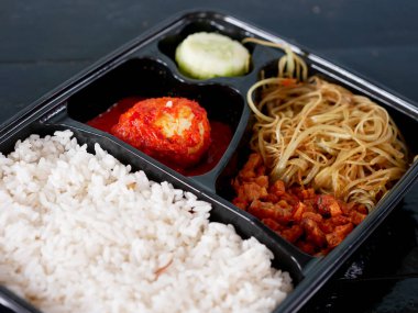 pirinç bento kutusu yanında balado yumurtaları, erişte, tempeh ve salatalık sebzeleri..
