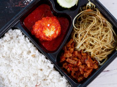 pirinç bento kutusu yanında balado yumurtaları, erişte, tempeh ve salatalık sebzeleri..