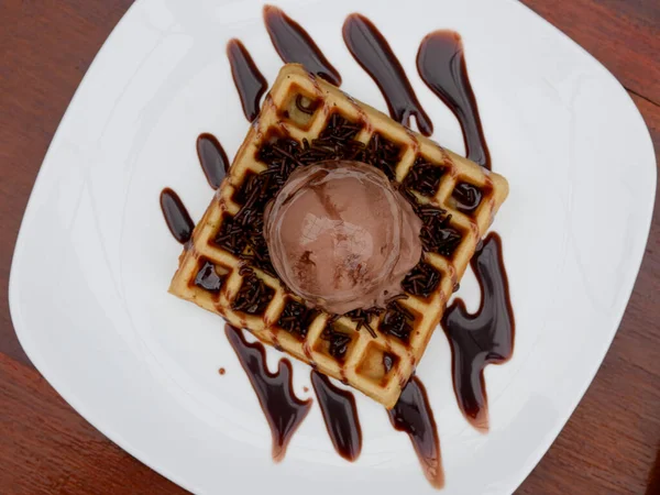 chocolate waffle with ice cream topping and chocolate sprinkles