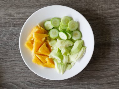 Beyaz tabakta mango, salatalık ve ananas salatası. Rujak, Endonezya 'dan geleneksel bir meyve salatası.