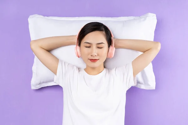 紫色の背景に隔離された上枕を持つアジアの女性 — ストック写真