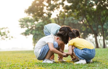 image of asian kids using magnifying glass in park