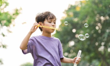 portrait of asian boy playing blowing bubbles