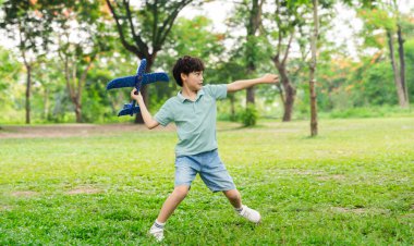image of boy playing with toy plane in park