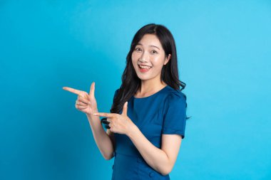 Mavi elbiseli güzel bir kadının portresi, mavi arka planda izole edilmiş.