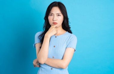 Mavi arka planda poz veren mutlu bir Asyalı kızın portresi.