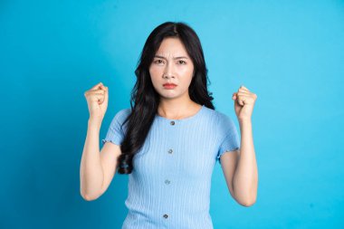 Mavi arka planda poz veren mutlu bir Asyalı kızın portresi.