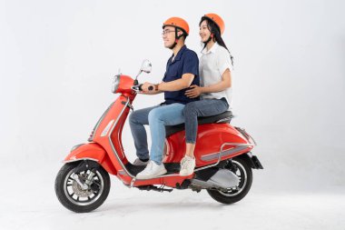 Asyalı bir çiftin beyaz arka planda scooter sürerken görüntüsü