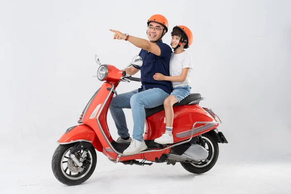 father and son wearing helmets and riding motorbikes