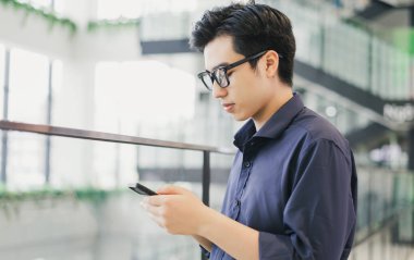 Asyalı iş adamı iş yerinde telefon kullanıyor.