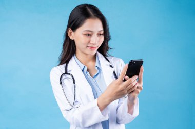 Mavi arka planda izole edilmiş genç bir kadın doktor portresi.